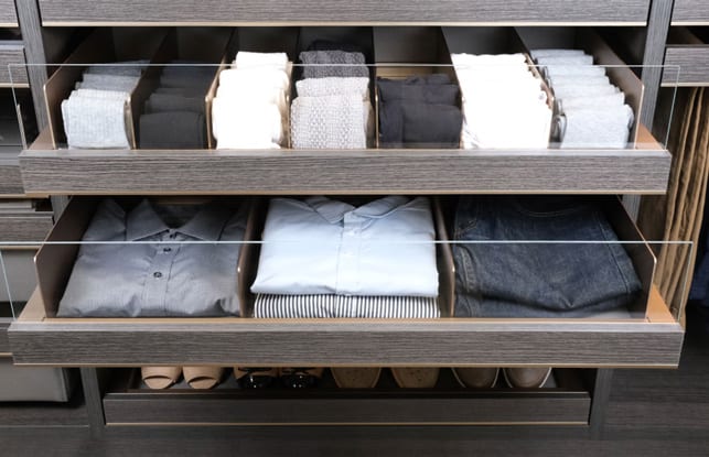 Clear front custom drawer holding men's socks and shirts with a natural wood grain finish by California Closets