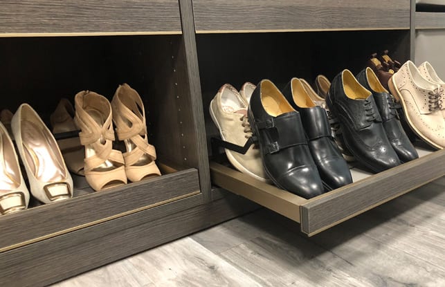 Pull out shoe storage drawer in a walk in closet shown in dark wood grain finish by California Closets